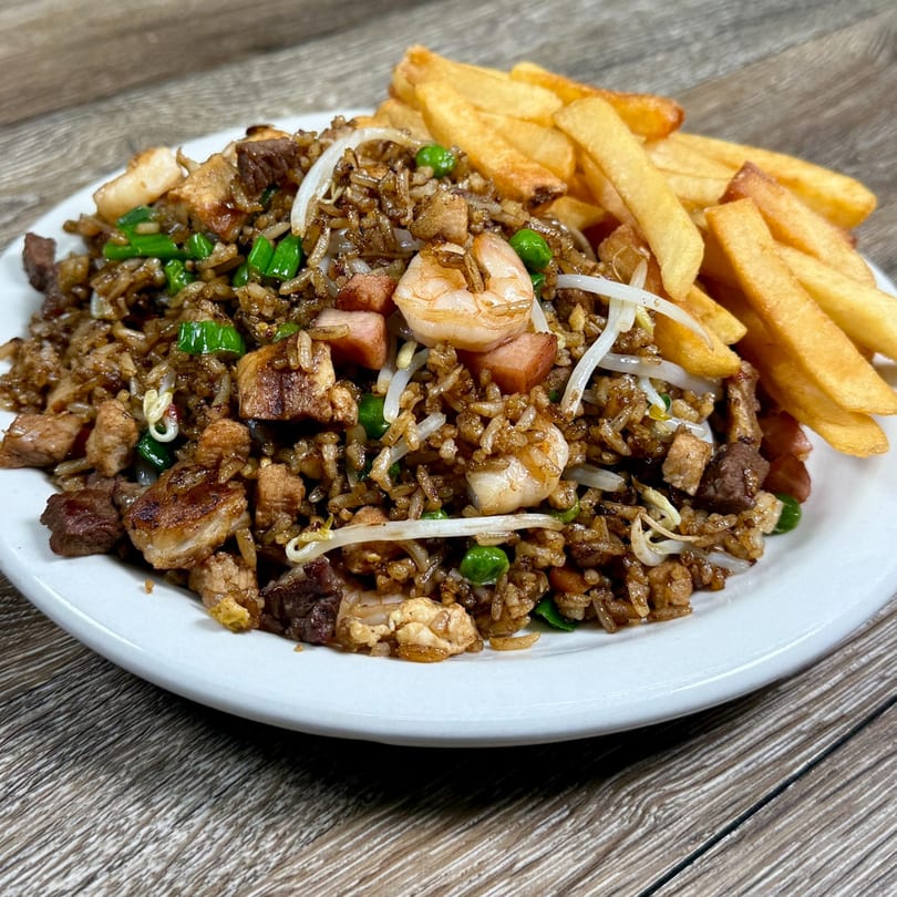 Venezuelan fried rice with shrimp, pork, beef, and vegetables, served with a side of french fries.